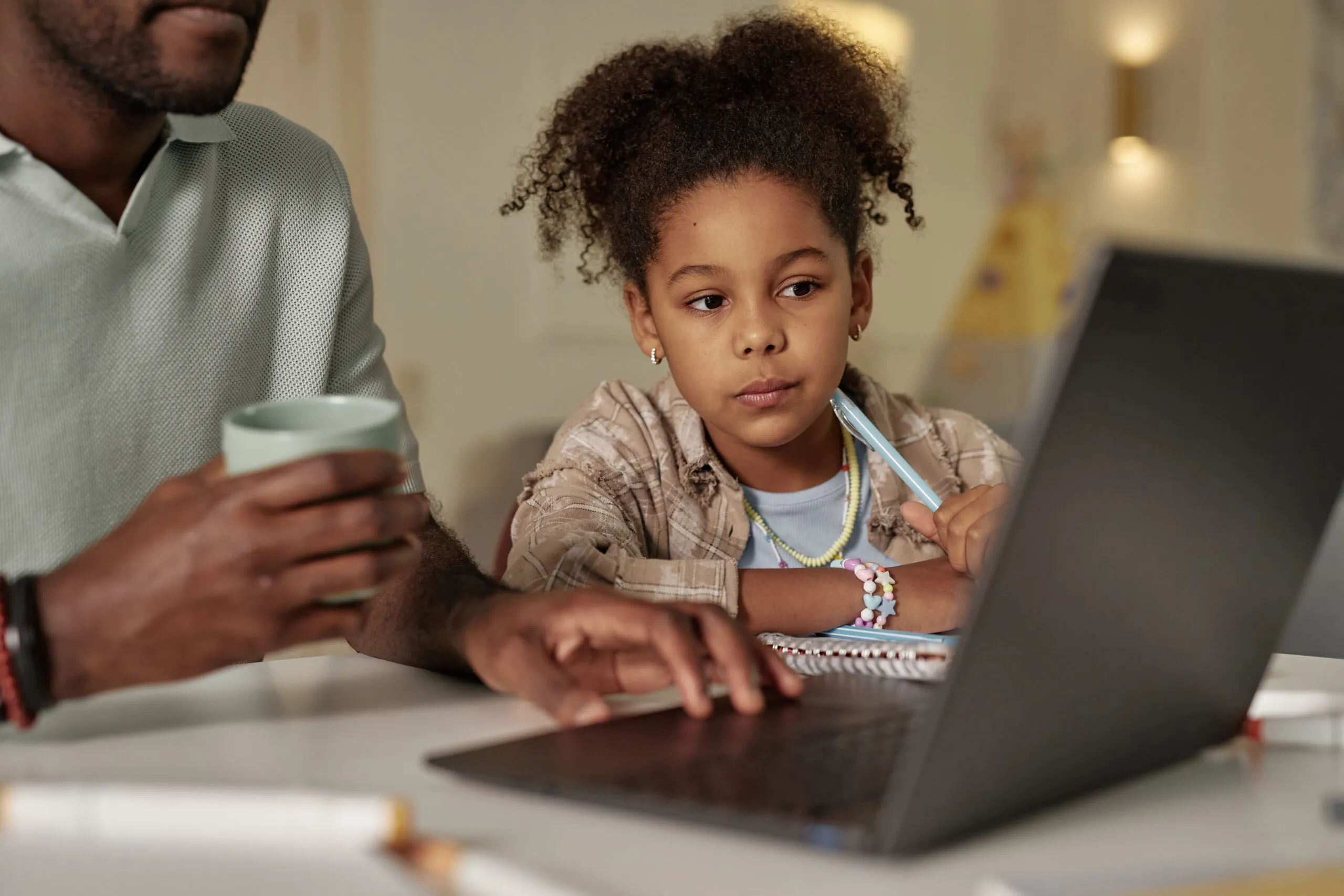 Meisje dat achter haar laptop zit samen met haar vader
